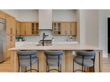 Modern kitchen showcasing wood cabinetry, stainless steel appliances, and a large center island with barstool seating at 8649 Robinson Ridge Dr, Las Vegas, NV 89117