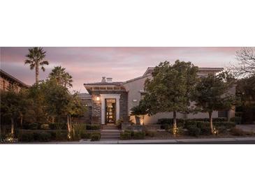 Charming single-story home featuring manicured landscaping and a welcoming stone entryway at sunset at 10305 Orkiney Dr, Las Vegas, NV 89144