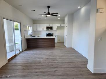 Bright open-concept living room featuring sleek wood floors and a modern kitchen with white cabinets at 2032 Jesse Scott St, Las Vegas, NV 89106