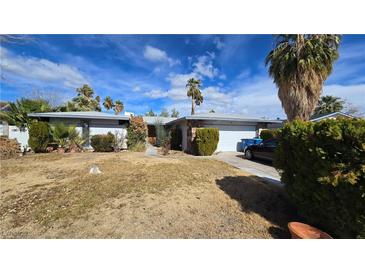 Charming single-story home with a two-car garage, desert landscaping, and mature palm trees at 3910 Woodhill Ave, Las Vegas, NV 89121