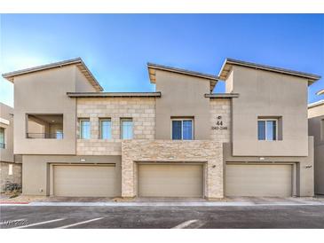 Modern townhome exterior with a two-car garage and light stone accents under a clear blue sky at 600 N Carriage Hill Dr # 1143, Las Vegas, NV 89138