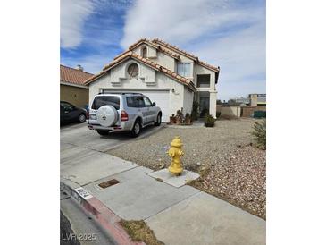 Two-story home featuring neutral stucco and tile roof in a desert landscape at 6624 Socorro Dr, Las Vegas, NV 89108