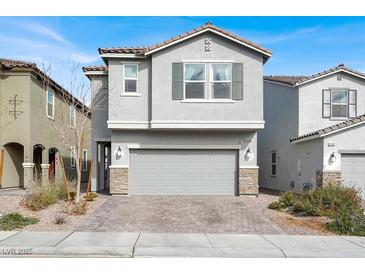 Two-story home featuring a two-car garage, gray stucco, and a paved driveway with desert landscaping at 6988 Sylmar Ave, Las Vegas, NV 89113