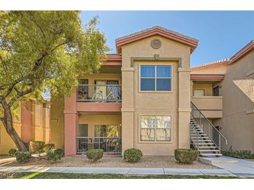 Inviting two-story condo with colorful facade, well-manicured landscaping and stairs to upper units at 8000 W Badura Ave # 1019, Las Vegas, NV 89113