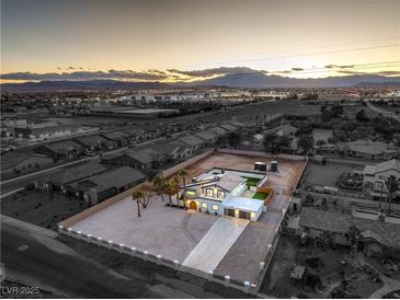 Expansive aerial view of a modern home with a spacious yard, set against a mountain backdrop at sunset at 8645 Edmond St, Las Vegas, NV 89139