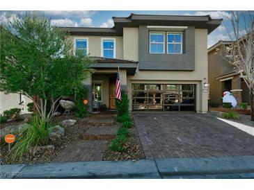 Contemporary two-story home featuring desert landscaping, a brick driveway, and a unique glass garage door at 10605 Harvest Green Way, Las Vegas, NV 89135