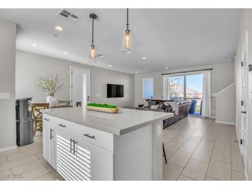 Bright, open-concept living room with island, modern lighting, and sliding doors to a balcony at 11230 Hidden Peak Ave # 207, Las Vegas, NV 89135