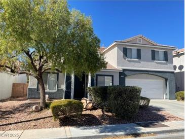 Two-story home with neutral paint scheme, manicured landscaping, mature tree, and an attached two-car garage at 6103 Harvest Dance St, North Las Vegas, NV 89031