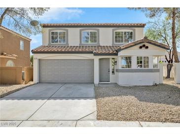 Two-story home with gray garage door, desert landscaping, and light-colored exterior paint at 8979 Green Jade Dr, Las Vegas, NV 89129