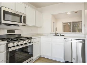 Bright kitchen featuring stainless steel appliances, white cabinets, and view into other living space at 9001 Marble Dr, Las Vegas, NV 89134