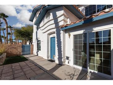 Two-story home featuring white stucco, a blue door, and large sliding glass doors at 924 Angel Star Ln, Las Vegas, NV 89145