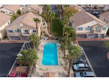 Aerial view of a community pool with palm trees, lounge chairs, and nearby residential buildings at 1292 Large Cap Dr # 3, Henderson, NV 89074