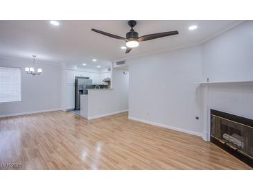 Bright living room featuring hardwood floors, a ceiling fan, fireplace, and open layout to the kitchen at 3060 Tarpon Dr # 104, Las Vegas, NV 89120