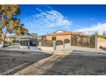 A charming single-story brick home with a landscaped front yard, secured by a wrought-iron fence and gate at 5162 Woodruff Pl, Las Vegas, NV 89120