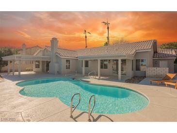 Inviting backyard pool with lounge chairs, perfect for relaxation and outdoor enjoyment under a vibrant sunset sky at 5904 Willowcreek Rd, North Las Vegas, NV 89031