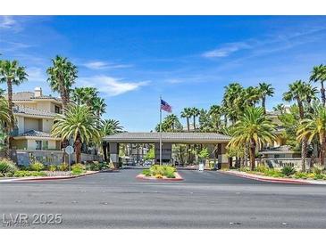 Welcoming community entrance featuring lush landscaping, palm trees and covered entry at 7115 S Durango Dr # 313, Las Vegas, NV 89113