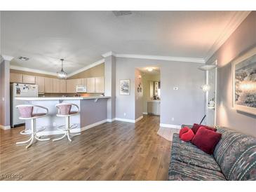 Bright living room featuring an open layout with hardwood floors and a breakfast bar overlooking the kitchen at 7909 Fossil Creek Ln # 202, Las Vegas, NV 89145