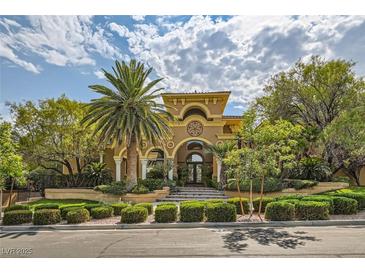 Elegant two-story home with mature landscaping, a palm tree, and a circular driveway at 9909 Moon Valley Pl, Las Vegas, NV 89134