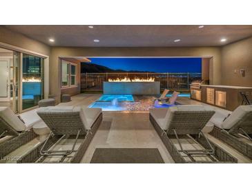 Inviting outdoor patio with a pool, fireplace, outdoor kitchen, and lounge chairs for relaxation at 10096 Amethyst Hills St, Las Vegas, NV 89148