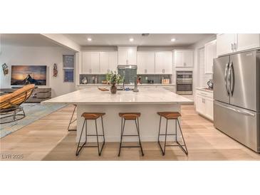 Bright open kitchen featuring a large marble island, stainless steel appliances, and modern white cabinetry at 12356 Grey Dunes Ave, Las Vegas, NV 89138