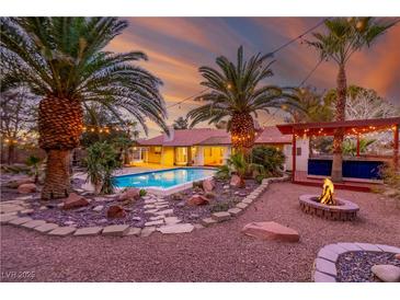 Inviting backyard with pool, fire pit, and covered patio, perfect for outdoor entertaining against a colorful sunset at 1561 Doran Dr, Las Vegas, NV 89123