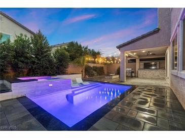 Inviting backyard pool with inset lighting, spa, lounge chairs, covered patio, and outdoor kitchen at 201 White Mule Ave, Las Vegas, NV 89148