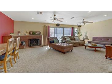 Bright living room featuring a fireplace, multiple sofas, ceiling fans and sliding glass doors to the backyard at 5109 Sugarfoot Ave, Las Vegas, NV 89107
