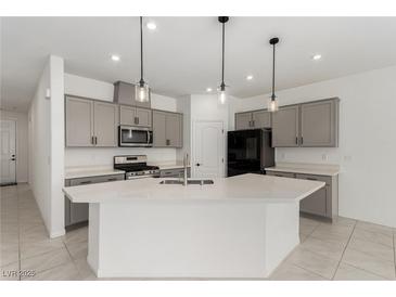 Modern kitchen features a large island, quartz countertops, gray cabinets, and stainless steel appliances at 5147 Stonecrop St, North Las Vegas, NV 89031