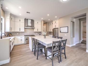 Bright kitchen with white cabinets, stainless steel appliances, a large island and seating at 11 Canoa Hills Dr, Henderson, NV 89052