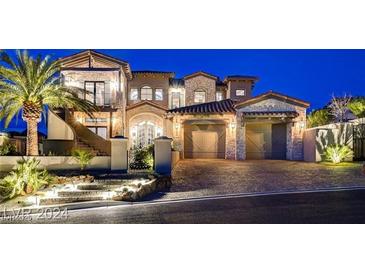Elegant exterior showcasing stone accents, curved staircase, and three-car garage, complemented by lush landscaping at twilight at 30 Via Tiberius Way, Henderson, NV 89011