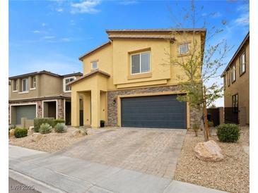 Two-story tan house with a brick driveway, stone accents, and a two-car garage at 4519 Stardusk Falls Ave, North Las Vegas, NV 89084