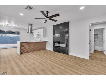 Open-concept living room with fireplace, ceiling fan, and wood-look floors at 4769 Via Renaldo, Las Vegas, NV 89103