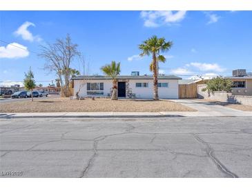 Charming single-story home featuring a well-maintained yard and desert landscaping, complemented by swaying palm trees at 4825 Randall Dr, Las Vegas, NV 89122