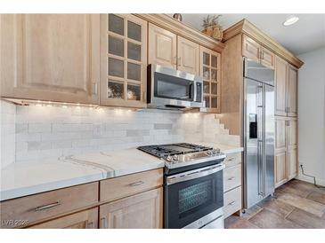 Modern kitchen featuring stainless steel appliances, custom cabinetry, and beautiful marble countertops at 1150 Calcione Dr, Henderson, NV 89011