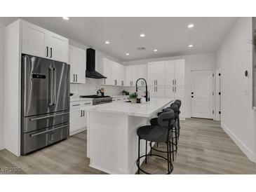 Bright, modern kitchen featuring white cabinets, stainless steel appliances, and an island with seating at 2008 Arbor Forest St, Las Vegas, NV 89134