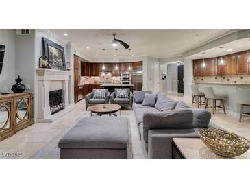 Open-concept living room showcases tile floors, gray furniture, and a stone fireplace at 30 Via Mantova # 202, Henderson, NV 89011