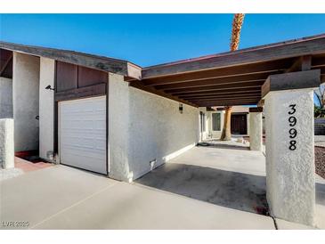 Contemporary house with attached garage, carport and desert landscaping with red and white rock at 3998 Foxgrove Dr, Las Vegas, NV 89147