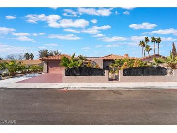 Charming single-story home with a beautiful front yard, mature palm trees, and secure gated entry at 5385 Ravendale Cir, Las Vegas, NV 89120