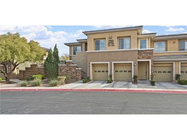 Multi-story townhouse with stone accents, tan exterior, well-manicured landscaping, and a two-car garage at 704 Peachy Canyon Cir # 101, Las Vegas, NV 89144