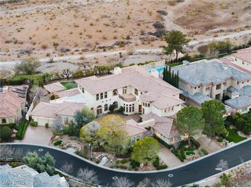 Expansive estate featuring a pool, mature landscaping, and a beige stucco exterior in a desert setting at 9325 Verlaine Ct, Las Vegas, NV 89145