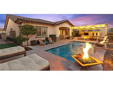 A luxurious backyard featuring a stunning pool with fire bowls and a covered outdoor living area at 12217 Tempestad Ave, Las Vegas, NV 89138