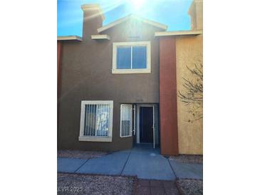 Two story exterior of home with neutral colors, security bars on windows and small front yard at 3850 Soda Springs Dr, Las Vegas, NV 89115