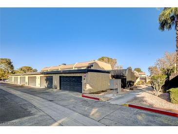 Charming townhome featuring attached garages and stucco siding, set against a backdrop of mature trees and clear blue skies at 4648 Comnor Hill Ln, Las Vegas, NV 89121