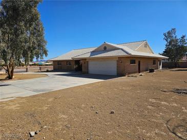 Single story home features a desert landscape, brick exterior, and attached two car garage at 4911 W Pebble Rd, Las Vegas, NV 89139