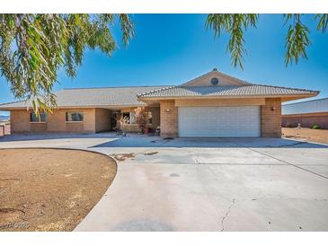 Single story home with a large driveway and a two car garage surrounded by desert style landscaping at 4911 W Pebble Rd, Las Vegas, NV 89139