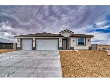 New construction home featuring a three car garage and desert landscaping at 6360 Montclair St, Pahrump, NV 89061