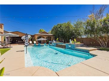 Inviting backyard pool features in-water seating and a stylish patio for relaxing and entertaining at 6391 Tempting Choice Ave, Las Vegas, NV 89131