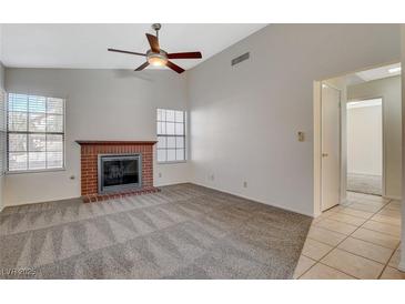 Inviting living room features a cozy brick fireplace and ceiling fan at 7719 Selby Ct, Las Vegas, NV 89147