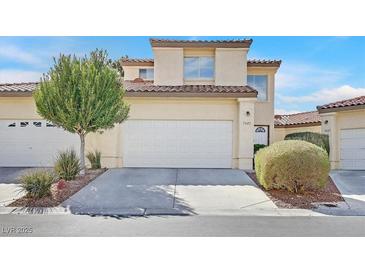 Charming two-story townhome showcasing a front yard with a tree and a convenient two-car garage at 5421 Painted Mirage Rd, Las Vegas, NV 89149