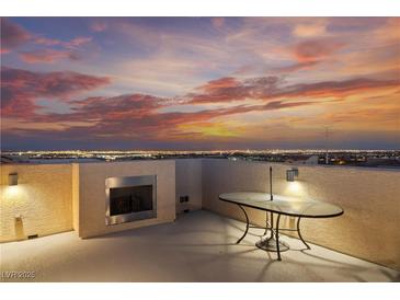 Enjoy city views and desert sunsets on this rooftop deck with an outdoor fireplace and modern glass table at 10725 Wrigley Field Ave, Las Vegas, NV 89166